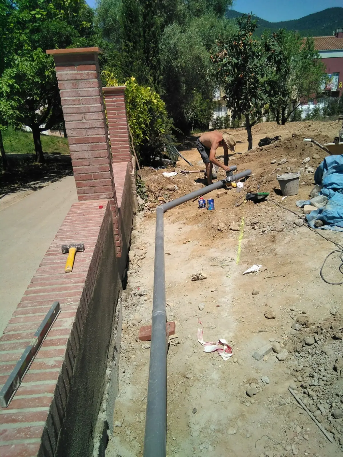 Vista de la zanja con tubería y pilares de ladrillo del acceso.