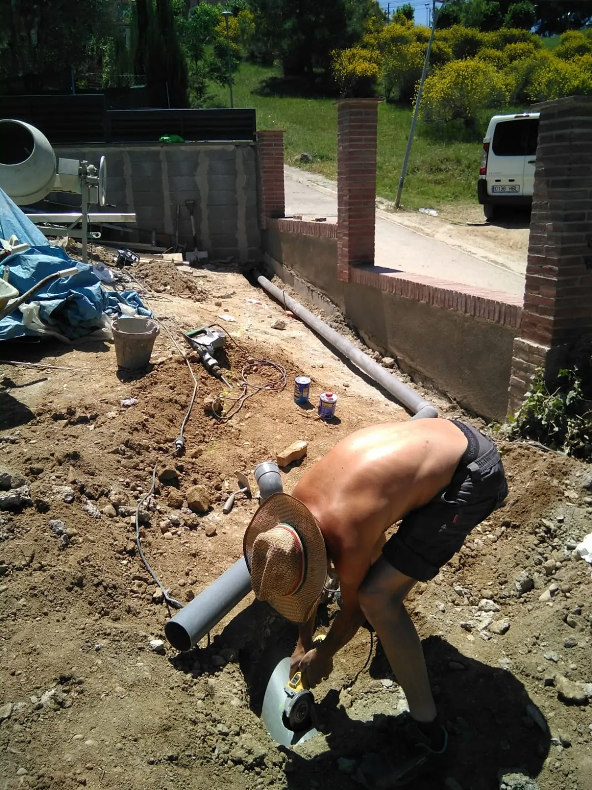 Operario instalando tubería de PVC. Muro de ladrillo de cerramiento al fondo.
