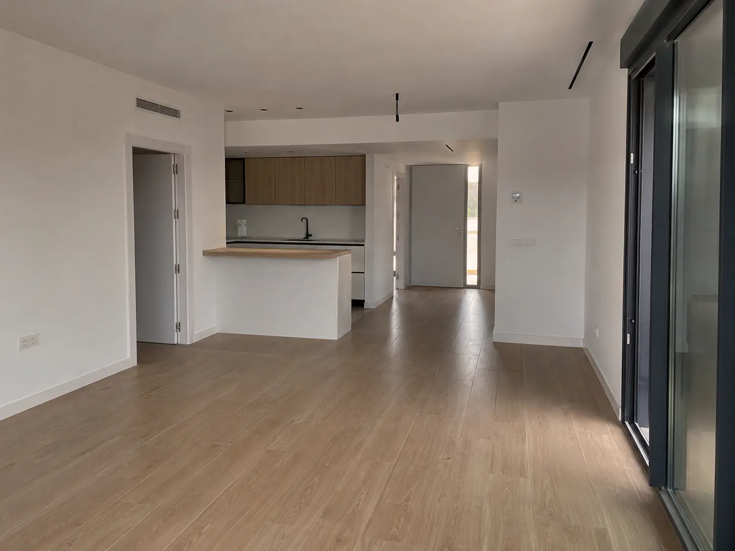 Inicio Salón comedor diáfano reformado con cocina de isla, suelo de tarima clara y grandes ventanales