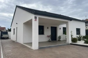 Casa de obra nueva de una sola planta con porche y fachada blanca de nueva construcción